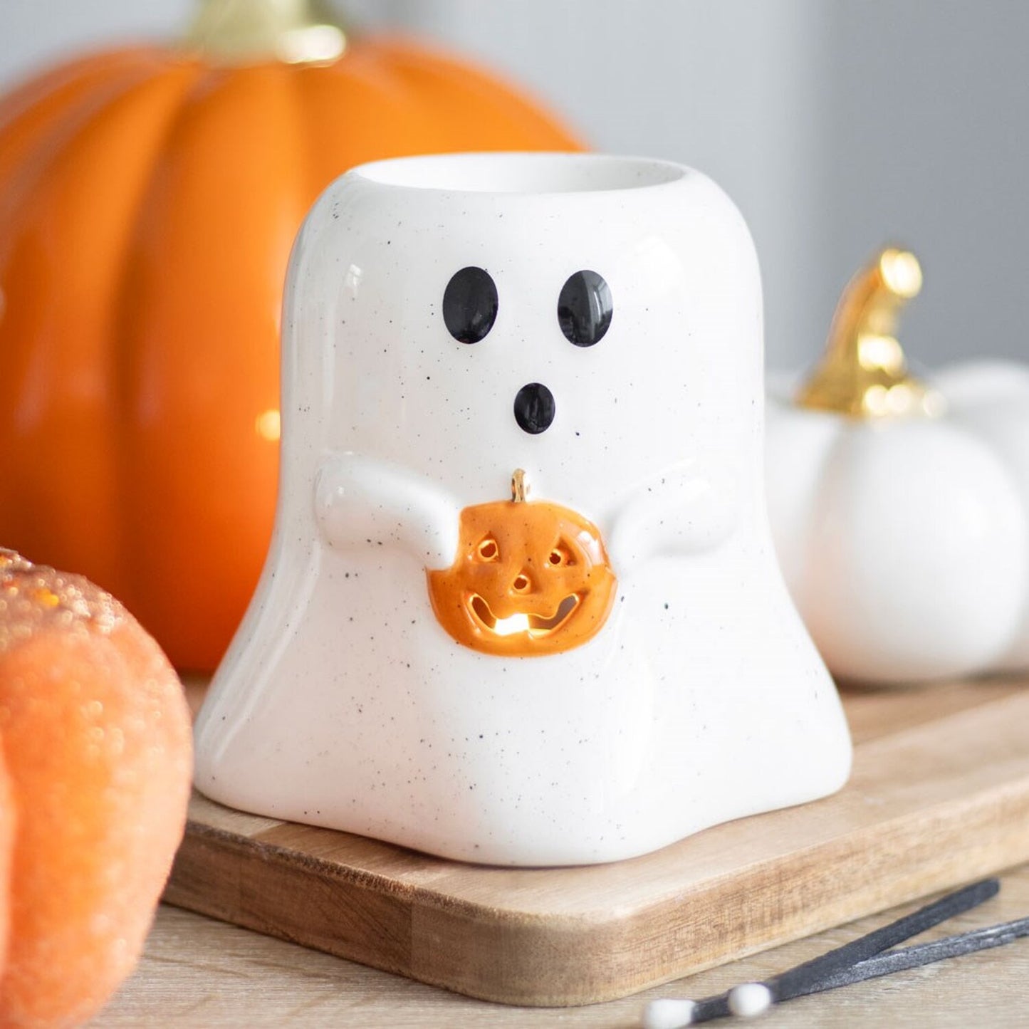 Gloriously Good ghost-shaped wax warmer holds a small orange pumpkin